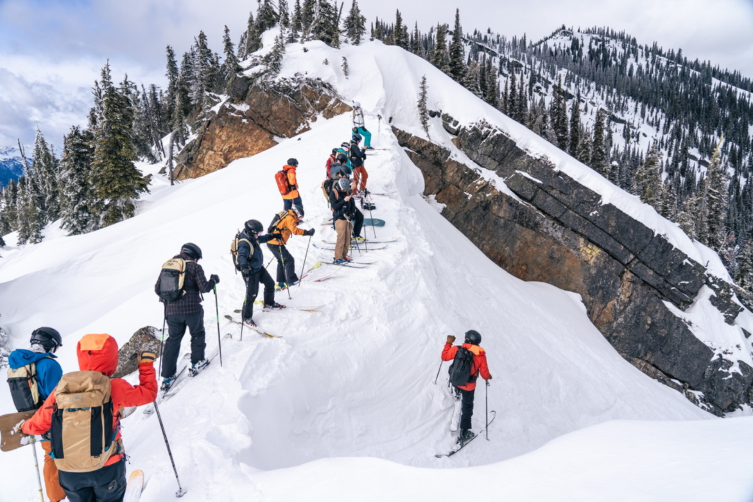 Skiers and snowboarders gathered along a snowy ridge